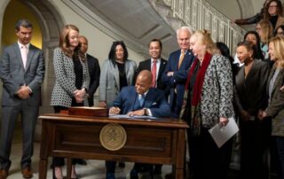 Mayor Eric Adams signing legislature with a group of people standing behind him