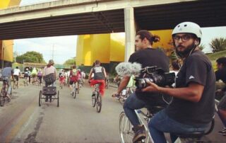film makers on bikes in a busy city street